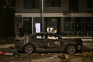 Un residente local mira un coche averiado en el patio.